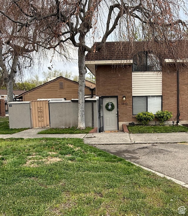 view of front of house featuring a gate, a front lawn, brick siding, and fence