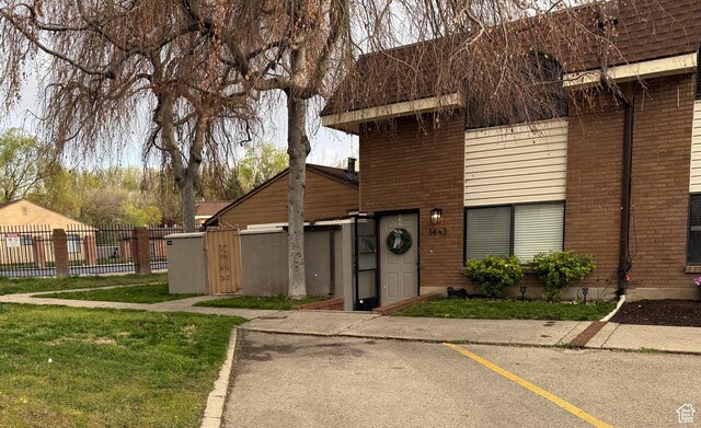 view of front of house with uncovered parking, fence, and brick siding