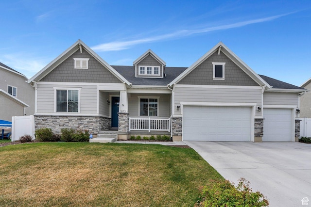 craftsman house with a porch, stone siding, concrete driveway, a garage, and a front yard