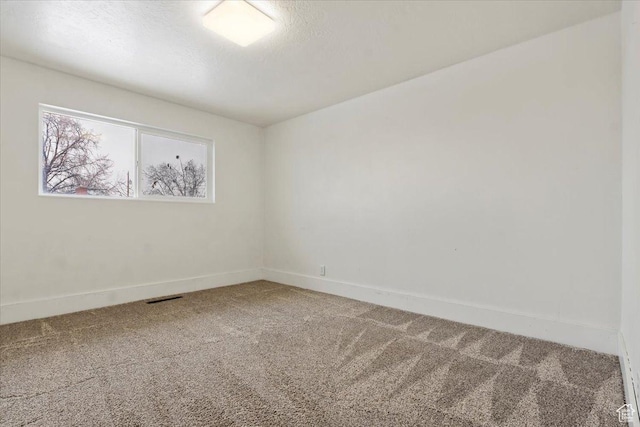carpeted empty room featuring a textured ceiling, visible vents, and baseboards