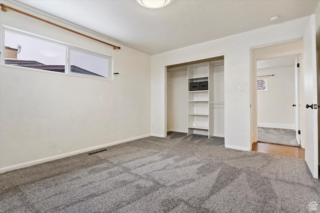 unfurnished bedroom featuring visible vents, baseboards, carpet flooring, and a closet