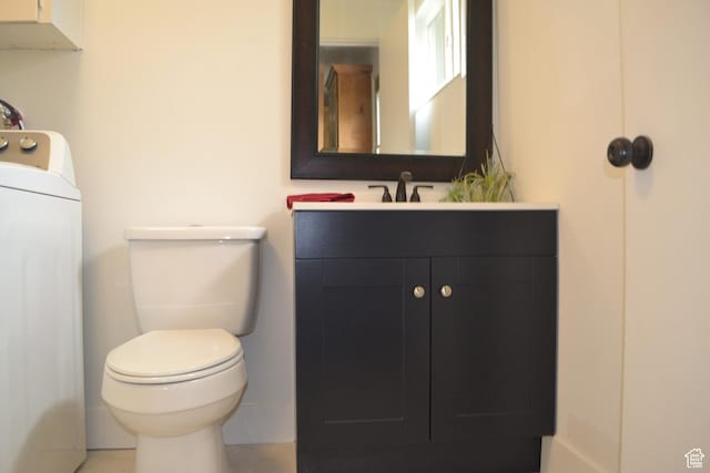 half bath with toilet, washer / clothes dryer, and vanity
