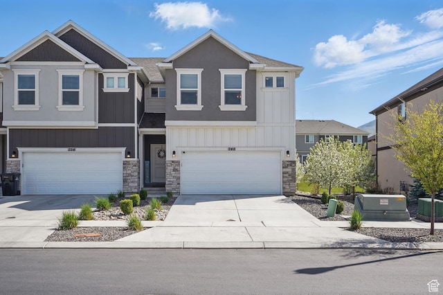 view of property with a garage, central AC, stone siding, and concrete driveway