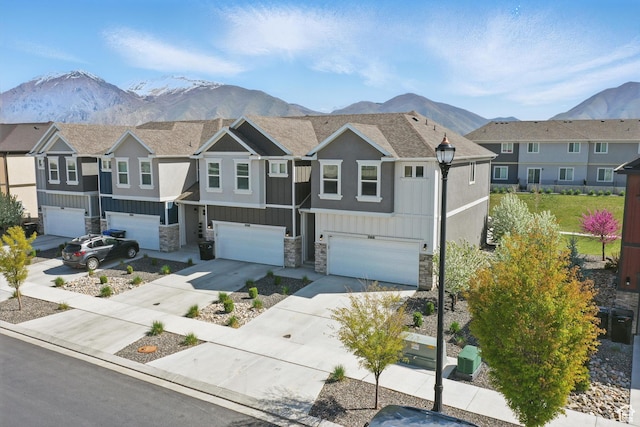 townhome / multi-family property featuring board and batten siding, driveway, a mountain view, and a garage