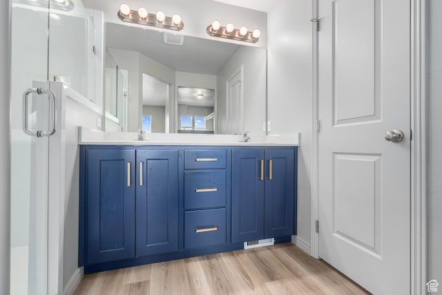 full bathroom featuring wood finished floors, a sink, visible vents, and double vanity