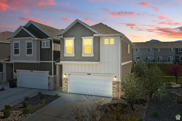 townhome / multi-family property featuring concrete driveway, stone siding, board and batten siding, and a garage
