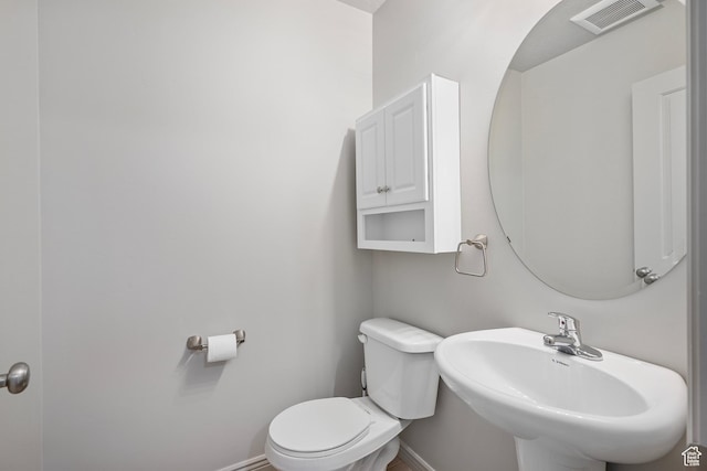 bathroom with visible vents, toilet, baseboards, and a sink