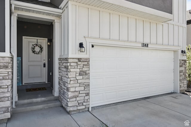 property entrance with stone siding, board and batten siding, and a garage