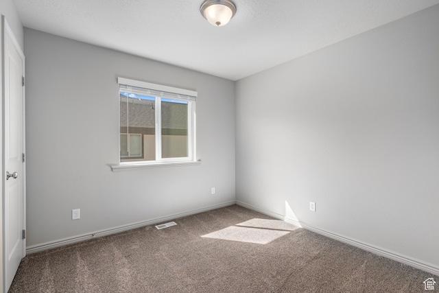 carpeted empty room featuring baseboards and visible vents