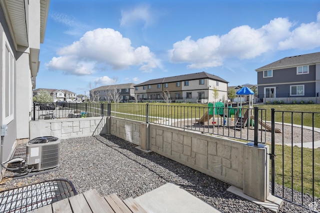 view of patio / terrace featuring a residential view, a fenced backyard, a playground, and central AC unit
