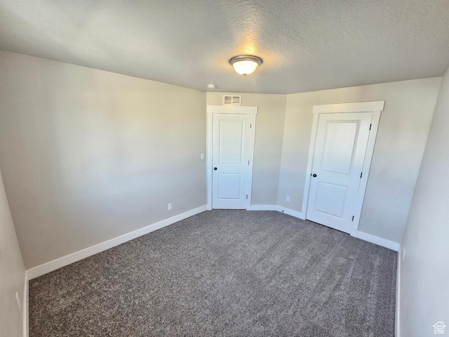 spare room with baseboards, carpet flooring, a textured ceiling, and visible vents