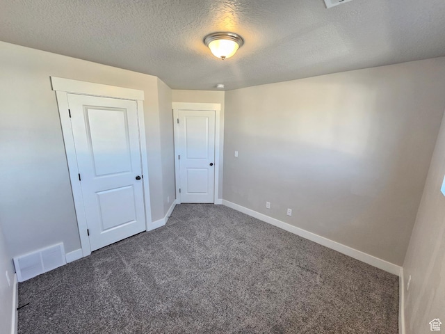 unfurnished bedroom featuring baseboards, a textured ceiling, visible vents, and carpet