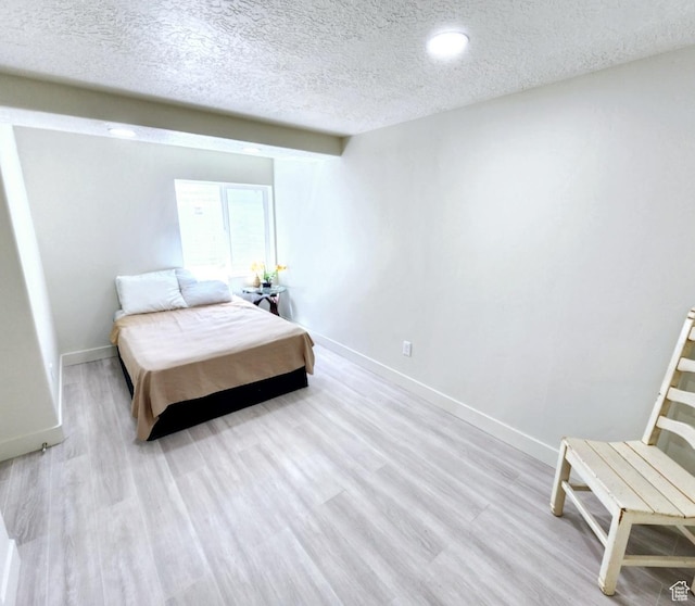 bedroom featuring baseboards, wood finished floors, a textured ceiling, and recessed lighting