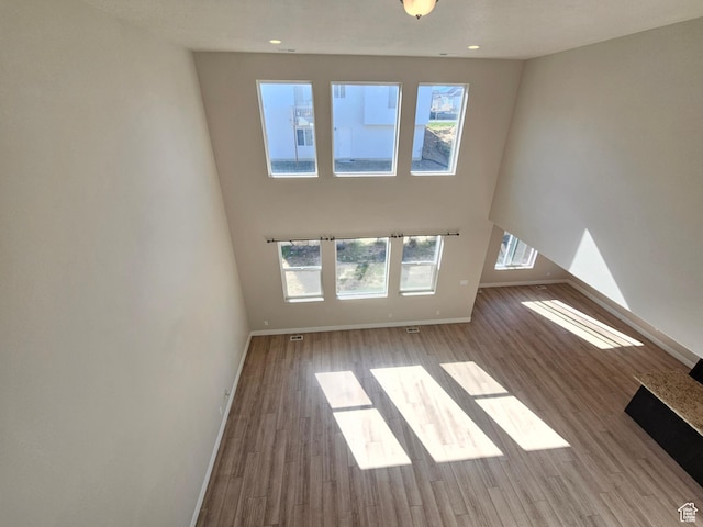 unfurnished living room with recessed lighting, wood finished floors, and baseboards