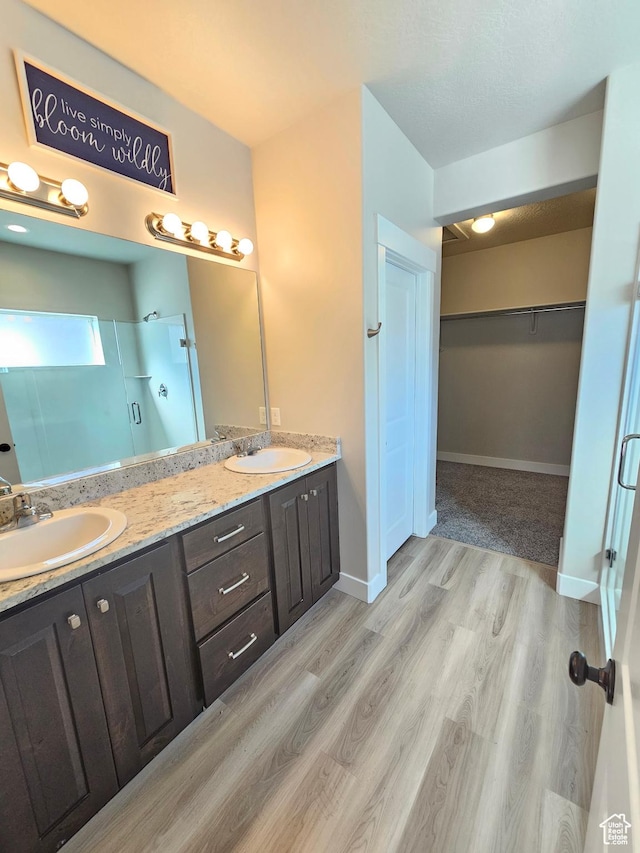 full bath featuring double vanity, a stall shower, and a sink