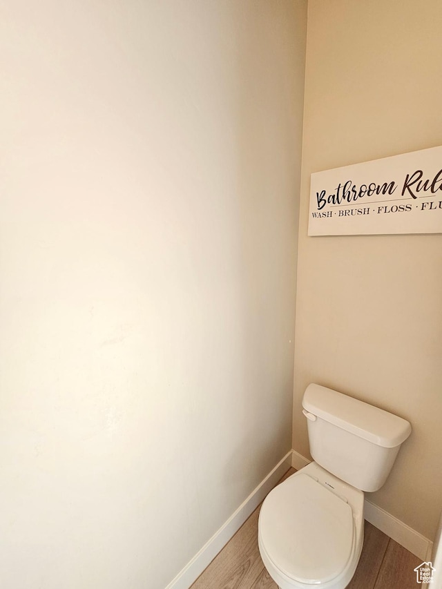 bathroom with wood finished floors, toilet, and baseboards