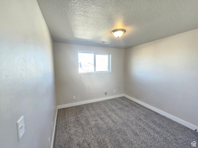 carpeted empty room with baseboards, visible vents, and a textured ceiling