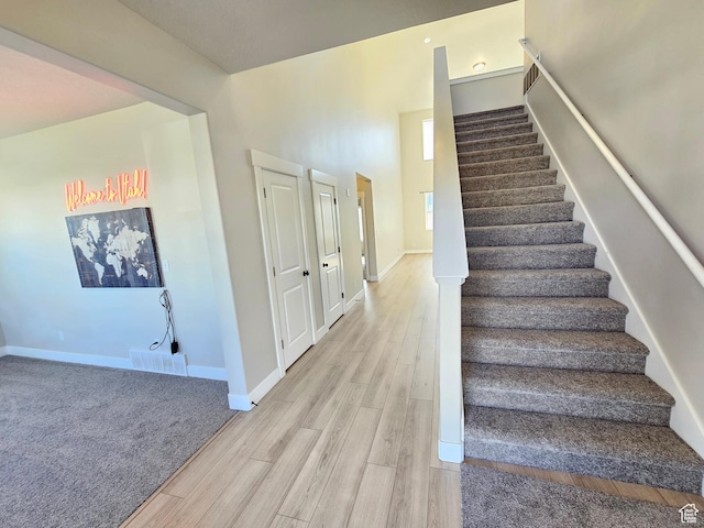 stairway featuring visible vents, baseboards, and wood finished floors