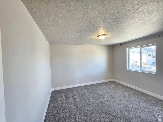 carpeted spare room featuring baseboards, visible vents, and a textured ceiling