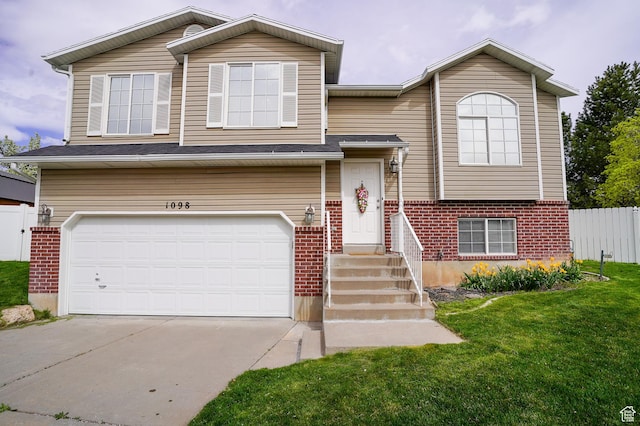 raised ranch with a garage, brick siding, and a front lawn