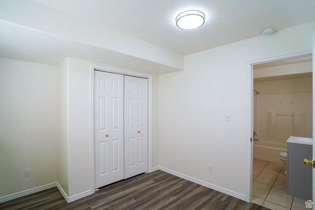 unfurnished bedroom featuring wood finished floors, a closet, and baseboards