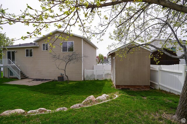 rear view of house with a storage unit, an outbuilding, a patio area, and cooling unit