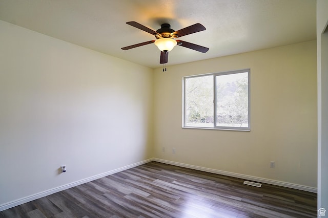 empty room with dark wood finished floors, a ceiling fan, and baseboards