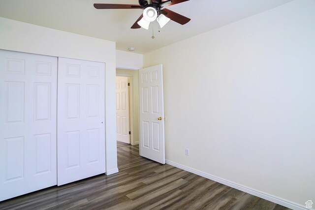 unfurnished bedroom featuring dark wood-style floors, baseboards, a closet, and a ceiling fan