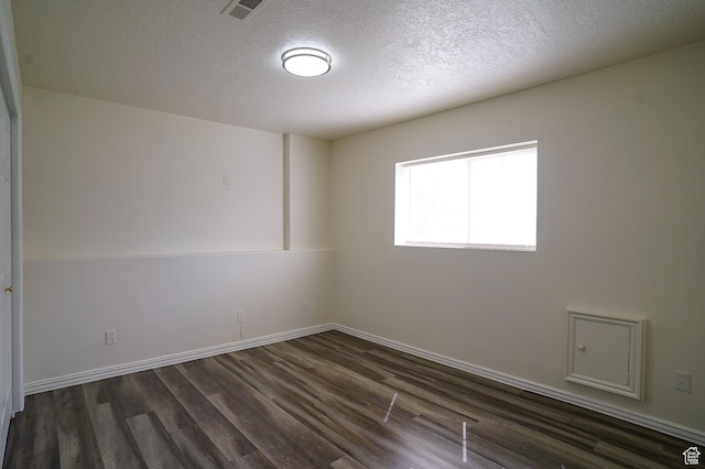 spare room featuring dark wood-type flooring, a textured ceiling, and baseboards