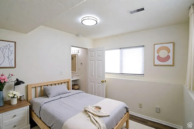 bedroom featuring baseboards, wood finished floors, and ensuite bathroom