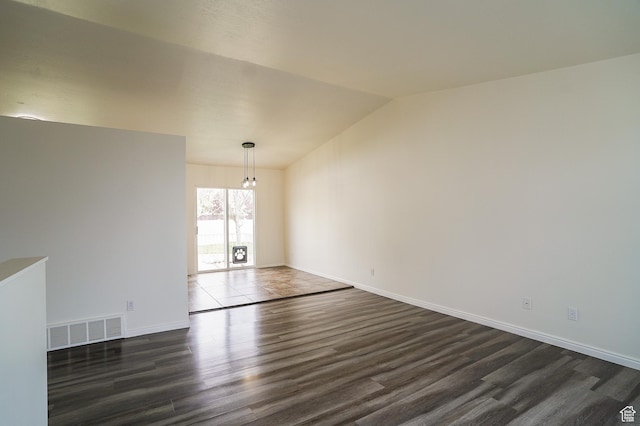 spare room with dark wood finished floors, vaulted ceiling, baseboards, and a chandelier