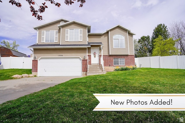 raised ranch featuring an attached garage, brick siding, and driveway
