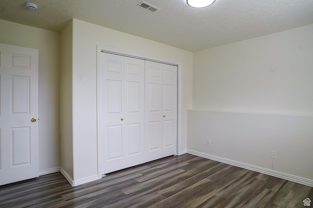 unfurnished bedroom with dark wood-style floors, a closet, baseboards, and a textured ceiling