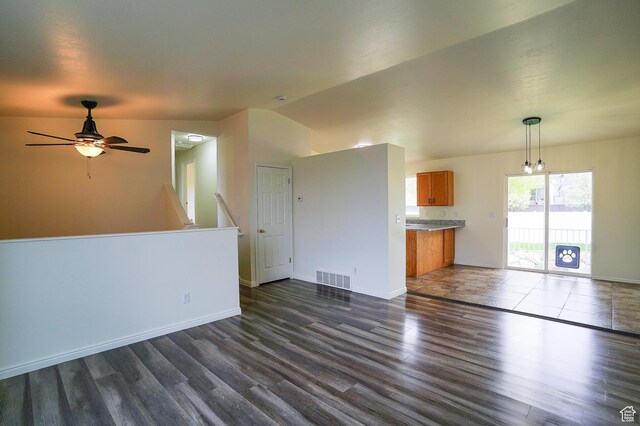unfurnished living room with dark wood-style flooring, baseboards, a ceiling fan, and vaulted ceiling