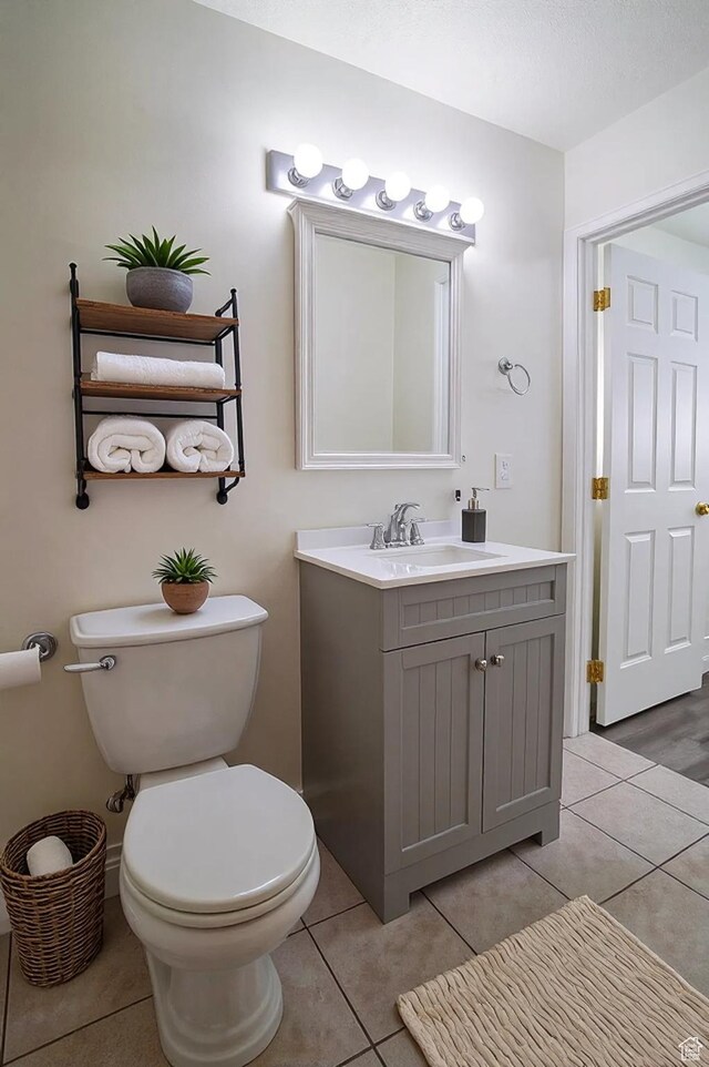 bathroom with toilet, tile patterned flooring, and vanity