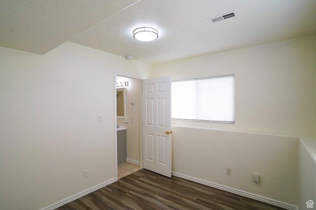 spare room featuring wood finished floors, a textured ceiling, baseboards, and a smoke detector