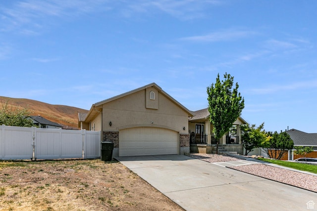 single story home featuring a gate, fence, concrete driveway, an attached garage, and stucco siding