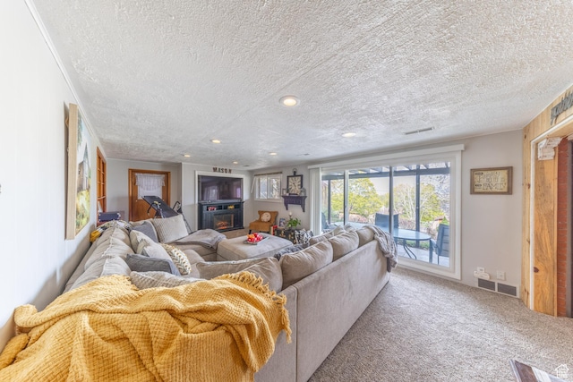 carpeted living room featuring visible vents, a textured ceiling, recessed lighting, and a lit fireplace
