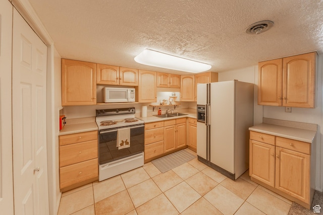 kitchen with light brown cabinetry, visible vents, white appliances, and light countertops