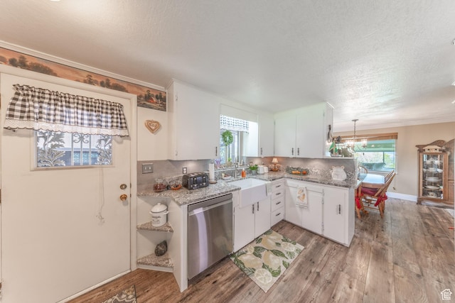 kitchen featuring a peninsula, light wood-style floors, stainless steel dishwasher, and a sink