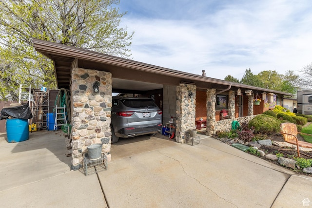view of front facade featuring stone siding, concrete driveway, and an attached carport