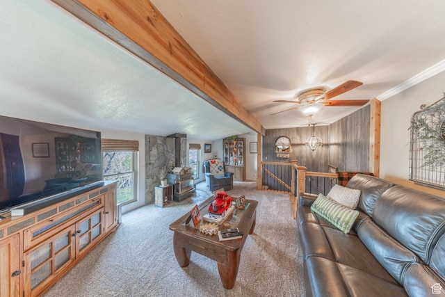 living area featuring crown molding, a ceiling fan, carpet floors, a wood stove, and wood walls