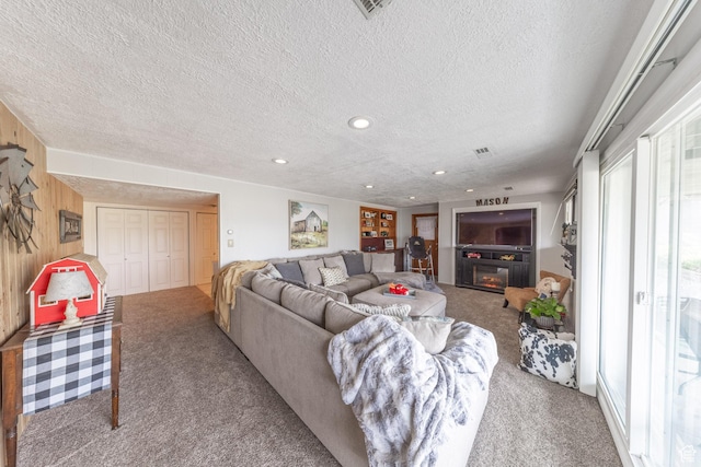 living area with recessed lighting, wood walls, a textured ceiling, and carpet