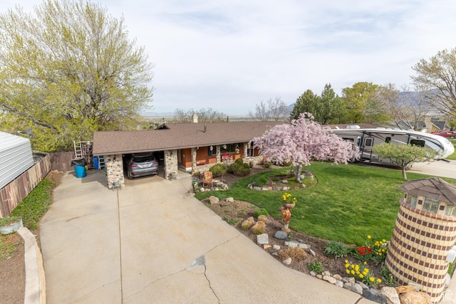 ranch-style house featuring a carport, roof with shingles, a front yard, and concrete driveway