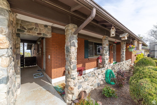 entrance to property featuring brick siding and covered porch