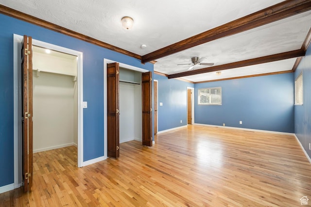unfurnished bedroom featuring baseboards, crown molding, beamed ceiling, and light wood-type flooring