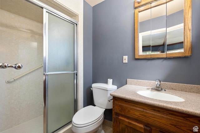 bathroom featuring a shower stall, toilet, and vanity