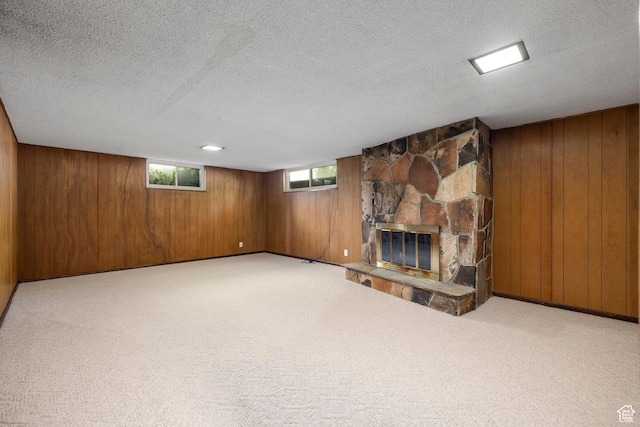 below grade area featuring a fireplace, wooden walls, carpet, and a textured ceiling