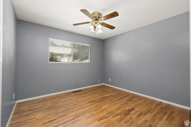 spare room featuring light wood finished floors, baseboards, ceiling fan, and visible vents