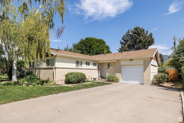 single story home featuring a garage, driveway, a front yard, and brick siding